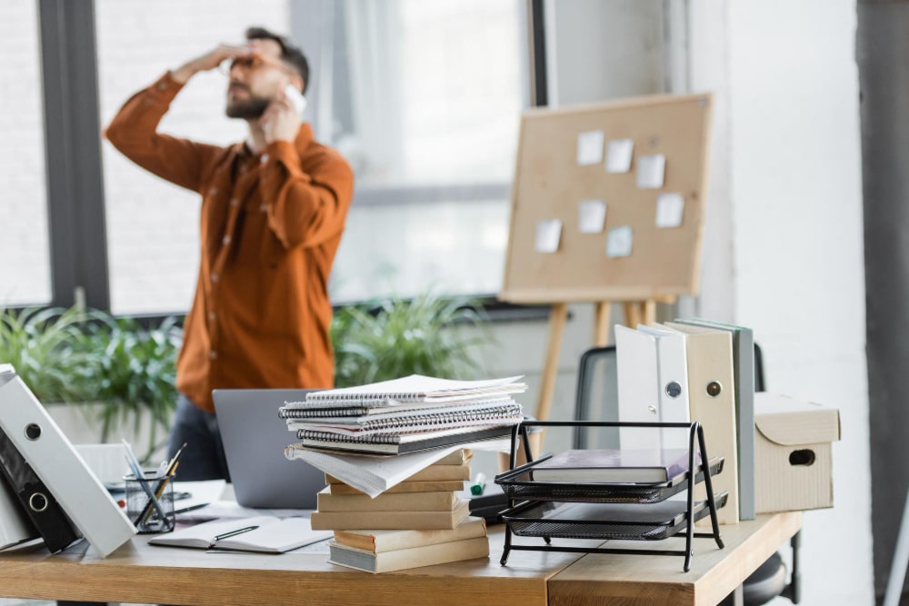 A startup founder works at a desk with a laptop, documents and calculator, managing administrative tasks