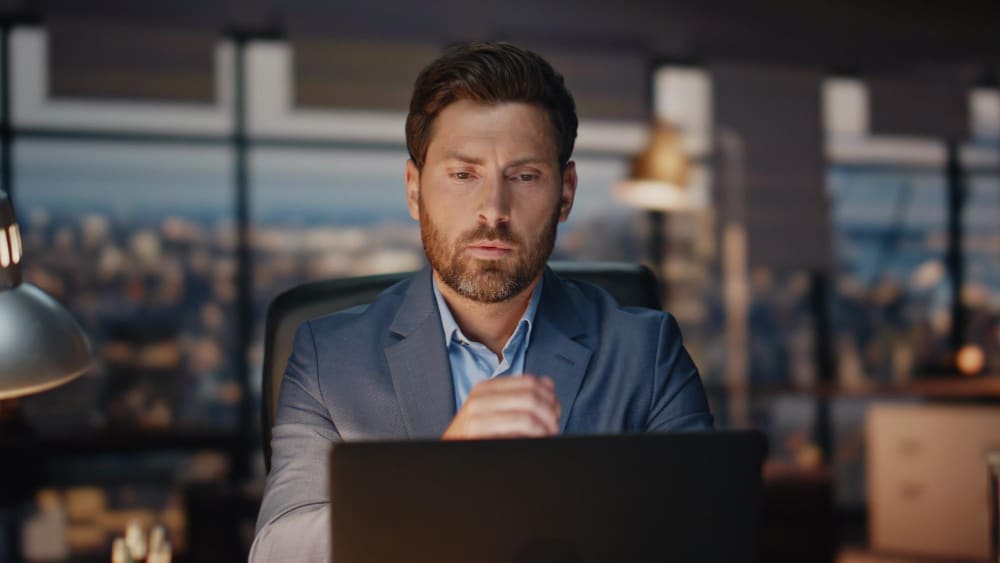 A founder working focused at a laptop in a home office, representing the deep work that becomes possible when admin is delegated