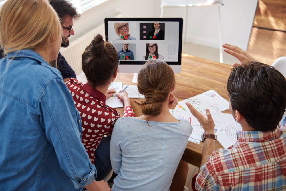 A remote team of professionals collaborates during a business meeting, representing the distributed working model managed EA services support