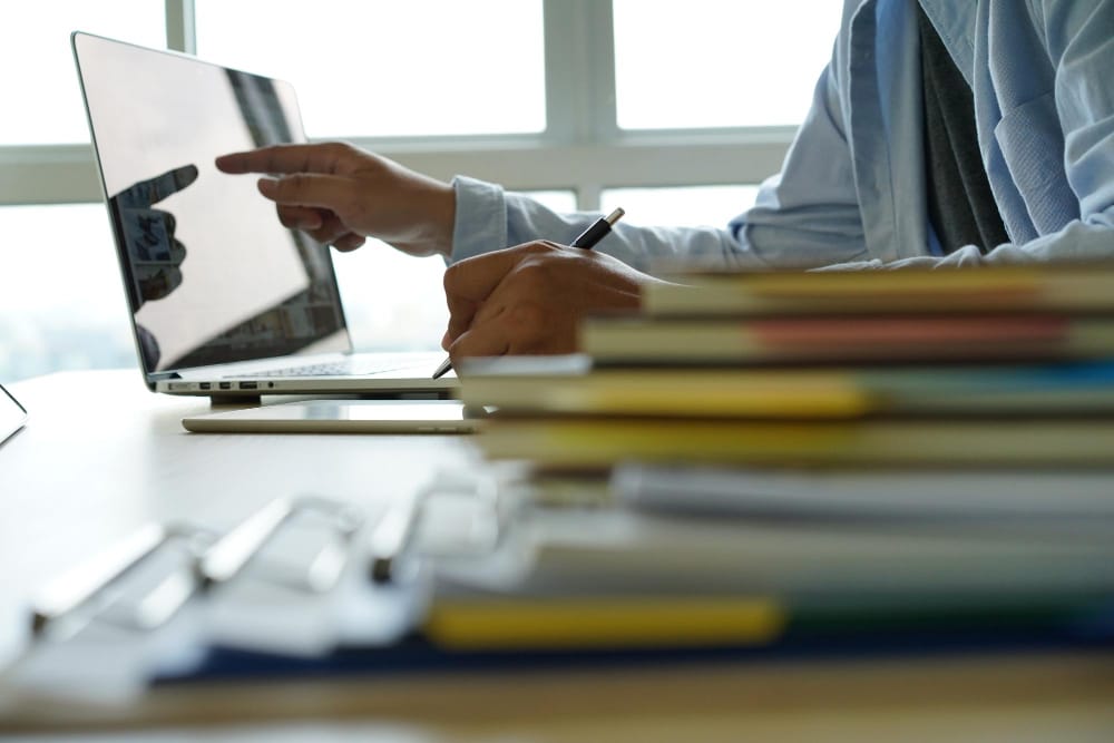 A founder recording and documenting a business process on a laptop to create a standard operating procedure