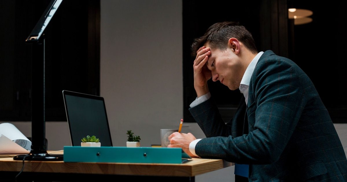 A stressed ceo sitting at his desk with his head in his hands