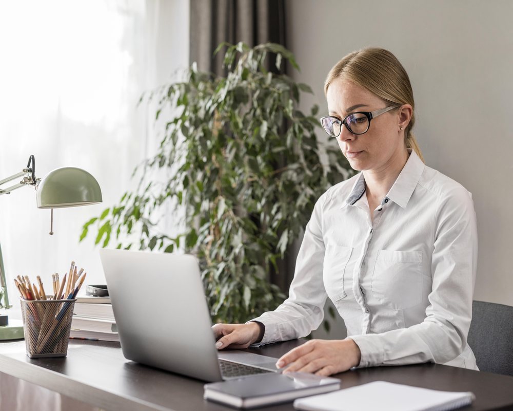 A virtual PA working at a laptop with a notebook, planning a founder's week