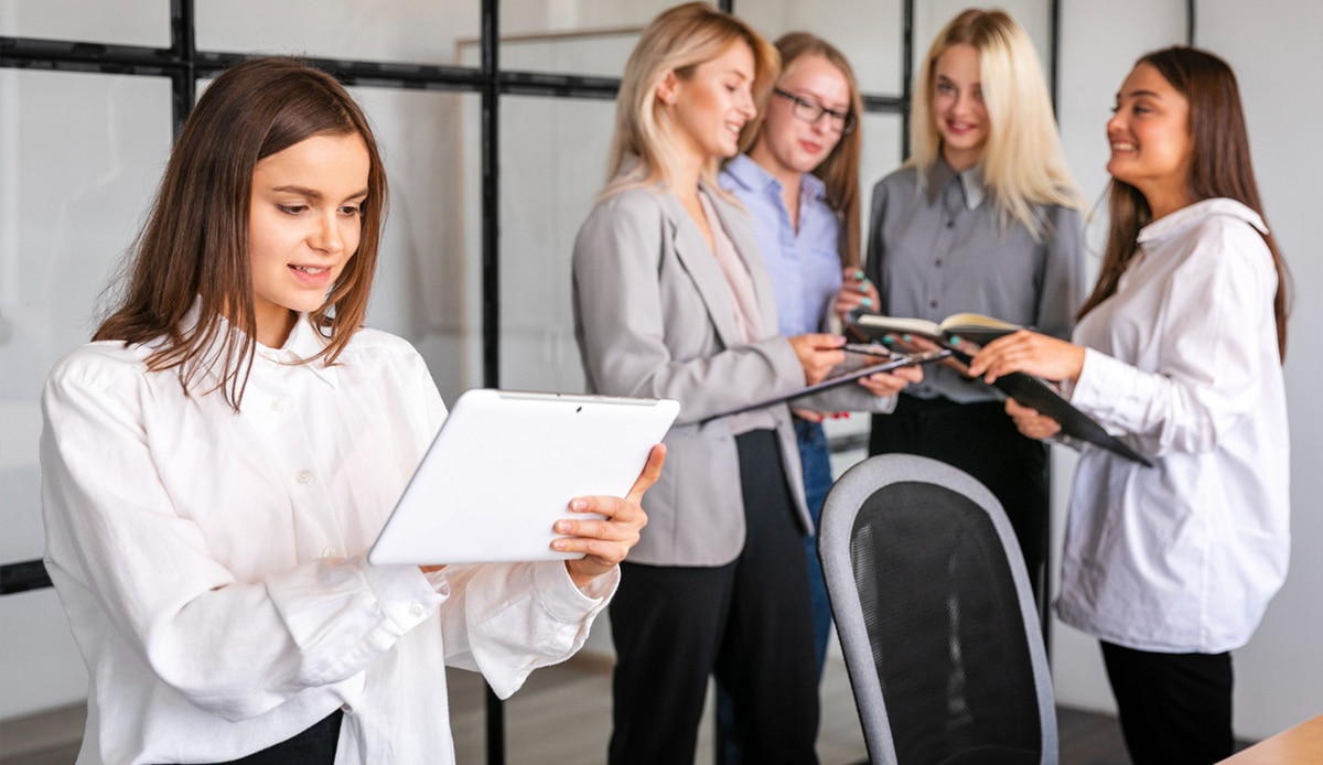 Multiple Assistants standing in office and looking at digital devices