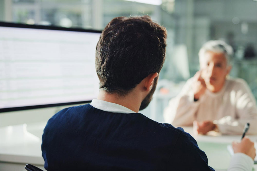 Two business professionals engaging in a focused discussion over a document, representing the process of aligning priorities and solving delegation challenges.