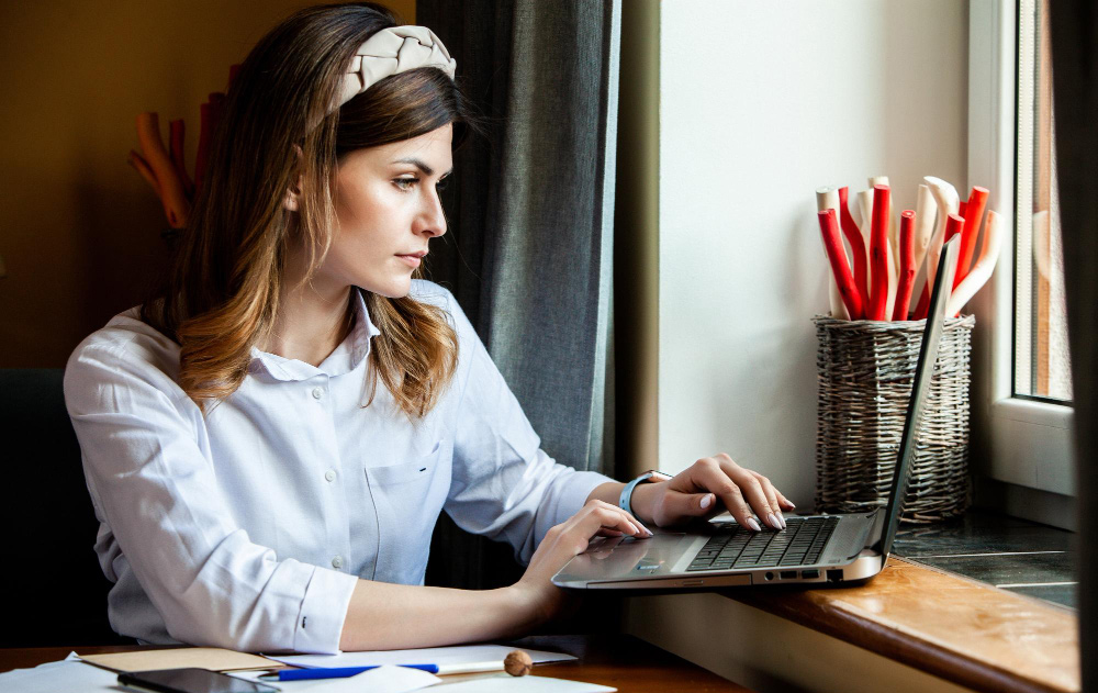 view of a professional workspace featuring a laptop, organized daily planner, and smartphone, representing the multitasking responsibilities of a CEO's executive assistant.